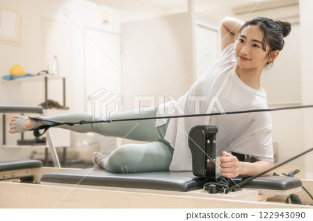Young woman doing machine pilates in indoor gym Young woman doing machine pilates in indoor gym 122943090