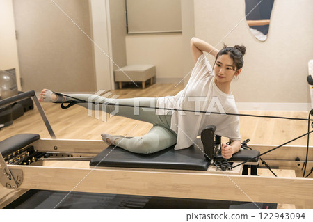 Young woman doing machine pilates in indoor gym 122943094
