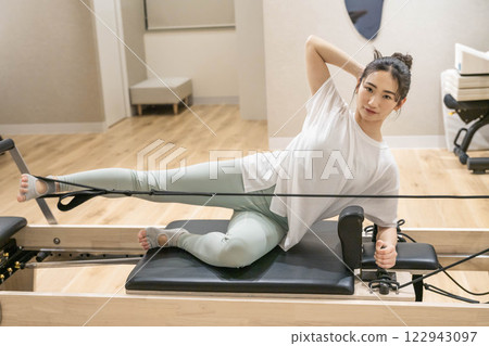 Young woman doing machine pilates in indoor gym Young woman doing machine pilates in indoor gym 122943097