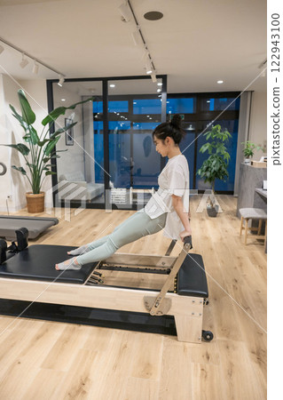 Young woman doing machine pilates in indoor gym Young woman doing machine pilates in indoor gym 122943100