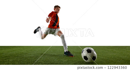 Dynamic image of focused boy, soccer player in orange jersey in motion on field, running towards ball against white background Dynamic image of focused boy, soccer player in orange jersey in motion on field, running towards ball against white background 122943360