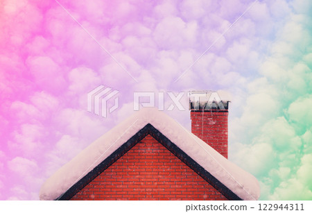 Roof and brick chimney covered with snow in winter with beautiful colorful gradient sky Roof and brick chimney covered with snow in winter with beautiful colorful gradient sky 122944311