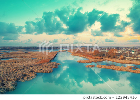 Rural landscape in the evening with beautiful sky. Aerial view of river and fields with village Rural landscape in the evening with beautiful sky. Aerial view of river and fields with village 122945410