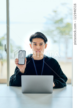A young man in his twenties holding a smartphone A young man in his twenties holding a smartphone 122946516