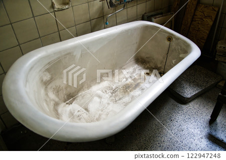 Old dirty bathtub showing neglect and abandonment in a bathroom Old dirty bathtub showing neglect and abandonment in a bathroom 122947248