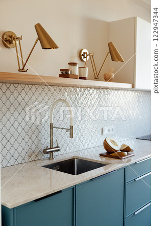 A modern kitchen with a blue set and a marble countertop A modern kitchen with a blue set and a marble countertop 122947344