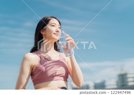 Woman hydrating during outdoor fitness Woman hydrating during outdoor fitness 122947496