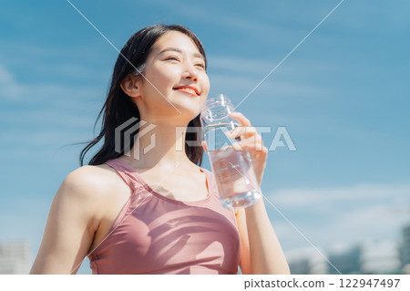 Woman hydrating during outdoor fitness Woman hydrating during outdoor fitness 122947497