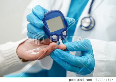 Asian doctor using digital glucose meter for check sample blood sugar level to treatment diabetes. 122947547