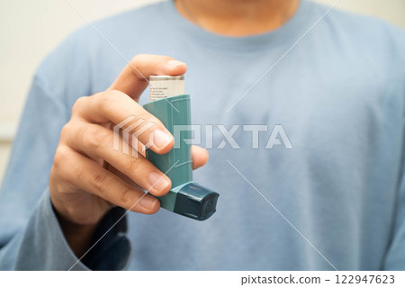 Asthma and chronic obstructive pulmonary disease COPD, Asian young man using metered dose inhaler MDI. 122947623