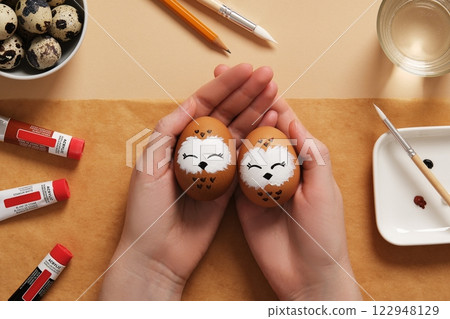 Hands holding Easter eggs with cute owls, hand-painted with acrylic paints, on a background of paints, brushes and palette. DIY concept Hands holding Easter eggs with cute owls, hand-painted with acrylic paints, on a background of paints, brushes and palette. DIY concept 122948129