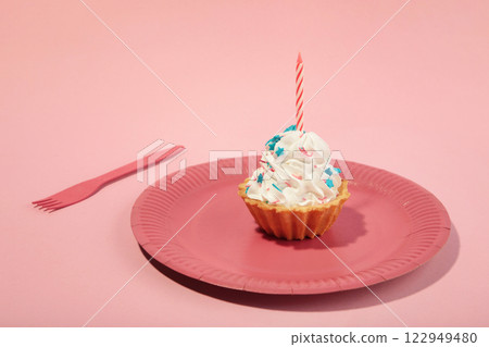 Delicious birthday cupcake with candle on pink plate and pink background. Creative photo Delicious birthday cupcake with candle on pink plate and pink background. Creative photo 122949480