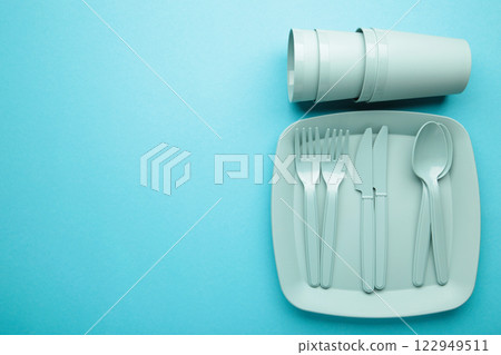 Bright plastic disposable tableware on blue background. Space for text 122949511
