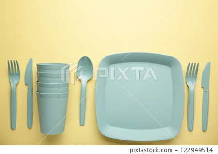 Bright plastic disposable tableware on yellow background. 122949514
