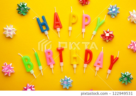 Text Happy Birthday with birthday asseccories, candles and confetti on yellow background. 122949531