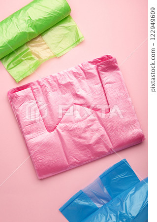 A lot of colored plastic bags rolls on a pink background. Vertical photo. 122949609