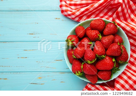 Ripe strawberries in blue bowl with napkin on blue background 122949682