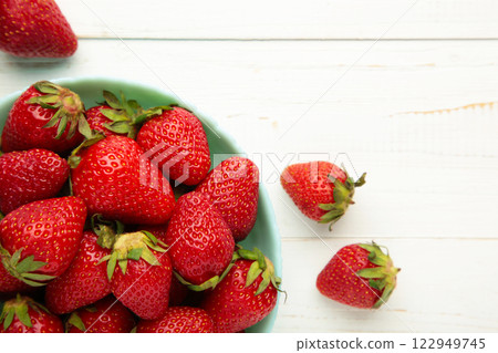 Ripe strawberries in blue bowl on white background 122949745