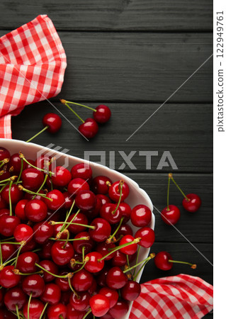 Fresh cherry in bowl with napkin on black background. Top view, copy space 122949761