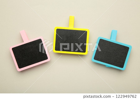 Blank wooden chalk plate on clothespins on grey background 122949762
