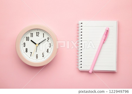 Empty white notebook top view with pink alarm clock on pink background Empty white notebook top view with pink alarm clock on pink background 122949796