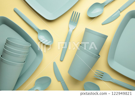 Bright plastic reusable tableware on a yelow background. 122949821