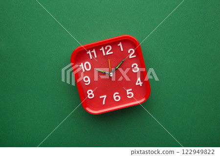Red wall clock on green background. Space for text Red wall clock on green background. Space for text 122949822