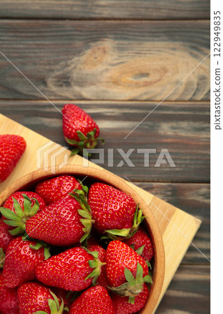 Ripe strawberries in a wooden bowl on cutting board 122949835
