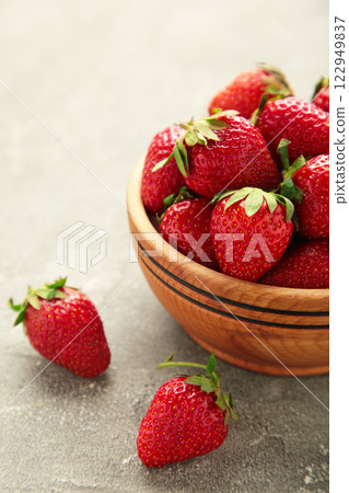 Ripe strawberries in a wooden bowl on grey background 122949837
