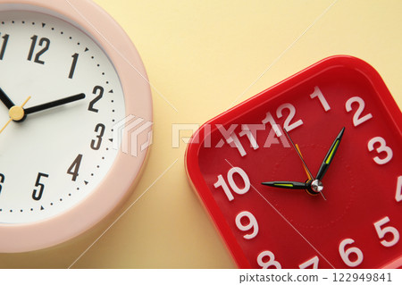 Pink and red wall clock on beige background. Vertical photo Pink and red wall clock on beige background. Vertical photo 122949841