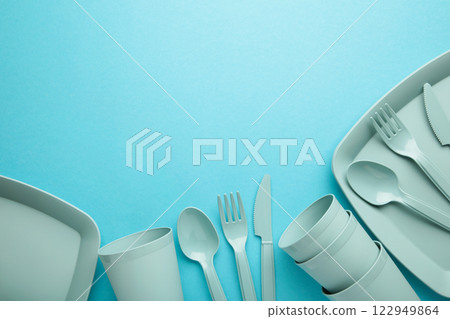 Bright plastic reusable tableware on a blue background. 122949864