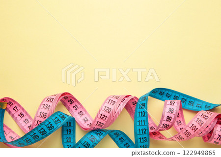 Blue and pink plastic measure tape with metric scale over on color beige background. Blue and pink plastic measure tape with metric scale over on color beige background. 122949865