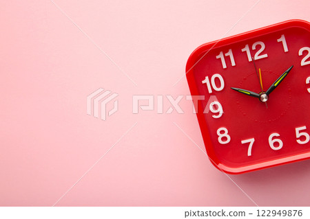 Red wall clock on pink background. Space for text 122949876
