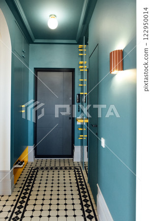 The front door of the apartment and a modern hallway. Stylish and refined interior of the room. Bright yellow accents on the blue built-in closet. The front door of the apartment and a modern hallway. Stylish and refined interior of the room. Bright yellow accents on the blue built-in closet. 122950014