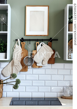 Stylish kitchen interior. Electric stove and kitchen utensils. Induction hob, potholders, wooden boards and a photo or picture frame. Stylish kitchen interior. Electric stove and kitchen utensils. Induction hob, potholders, wooden boards and a photo or picture frame. 122950029