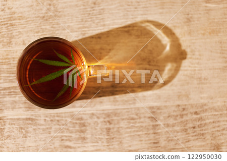 A transparent cup of delicious strong black tea with a cannabis leaf A transparent cup of delicious strong black tea with a cannabis leaf 122950030