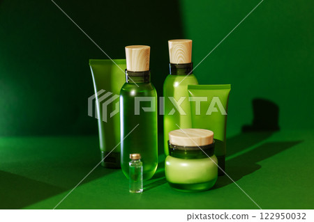 A set of layouts for cosmetic products. The mockups are a transparent and translucent bottle with lid, a tubes and a jar of cream. Green background. A set of layouts for cosmetic products. The mockups are a transparent and translucent bottle with lid, a tubes and a jar of cream. Green background. 122950032