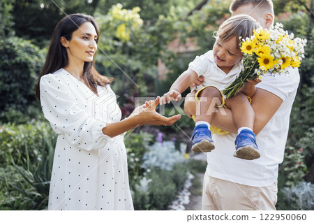 Young cute family in white clothes are playing in garden or park. Young cute family in white clothes are playing in garden or park. 122950060