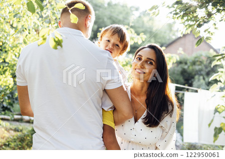 Cute family in light casual clothes in garden on terrace of their house. Cute family in light casual clothes in garden on terrace of their house. 122950061