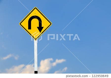 A black U turn symbol is prominently displayed on a bright yellow sign on blurred sky background. 122950649