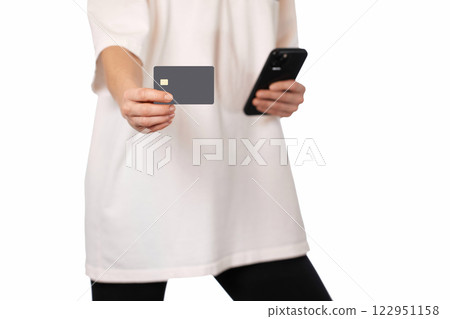 woman in white t-shirt holding mobile phone and black premium credit bank card on white background. Online shopping. woman in white t-shirt holding mobile phone and black premium credit bank card on white background. Online shopping. 122951158