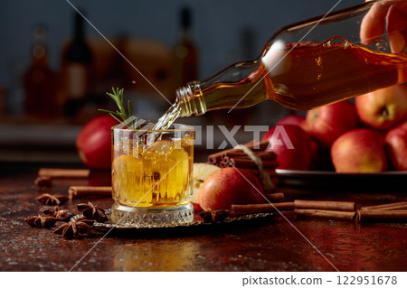 Apple cider is poured from a bottle into a crystal glass. 122951678