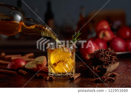 Apple cider is poured from a bottle into a crystal glass. Apple cider is poured from a bottle into a crystal glass. 122951680