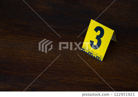 Yellow crime scene evidence marker number 3 on the floor in the room. High quality photo Yellow crime scene evidence marker number 3 on the floor in the room. High quality photo 122951921