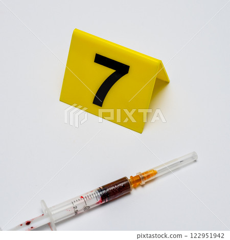 crime investigation evidence marker. syringe near yellow marker number 7 on white background. High quality photo crime investigation evidence marker. syringe near yellow marker number 7 on white background. High quality photo 122951942