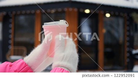 Bright pink cup against glowing winter backdrop evokes cozy moment of relaxation, letting cozy thoughts warm chilly day, as cozy ambiance invites viewers to embrace gentle calm forever. 122952091