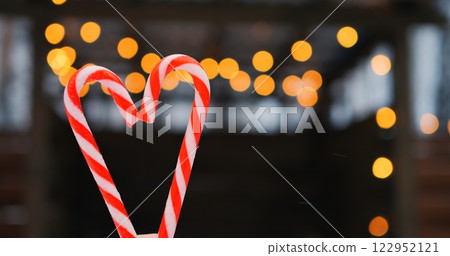 Candy cane heart frames swirling red stripes as bokeh twinkles behind, letting bokeh fill airy background with dreamy holiday mood, gracefully revealing bokeh enchantment for seasonal wonder. 122952121