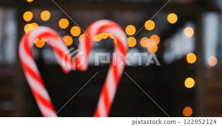 Candy cane heart glimmers under twinkling winter lights, reflecting love that warms chilly breeze, letting love expand holiday spirit, so love bonds hearts in cozy Valentines vibe. 122952124
