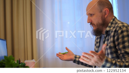 Bald man talking on video call, revealing fatigue from nonstop work, letting fatigue erode mental clarity, cautioning how fatigue undermines well-being without proper breaks. Drinks coffee 122952134