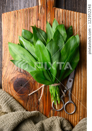 Bunch of vibrant green bear's garlic on a wooden cutting board Bunch of vibrant green bear's garlic on a wooden cutting board 122952248